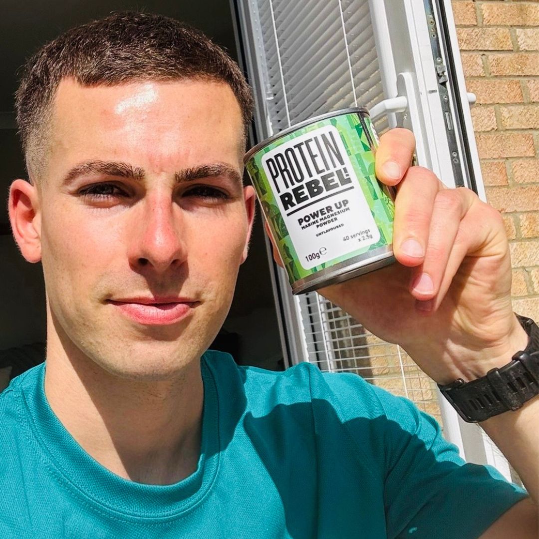 Man holding a 'Protein Rebel' container outdoors