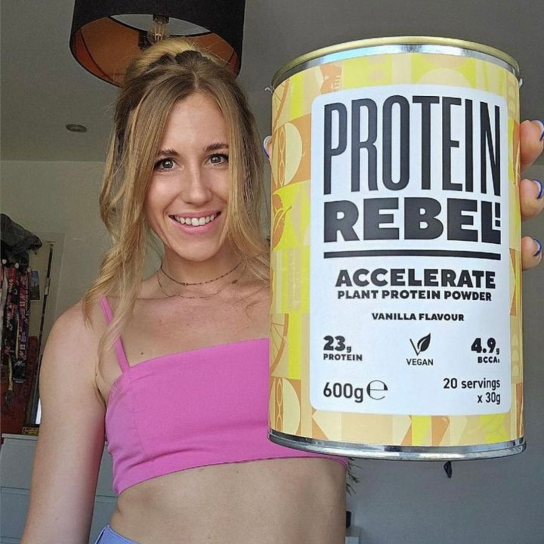 Person holding a can of Protein Rebel Accelerate plant protein powder