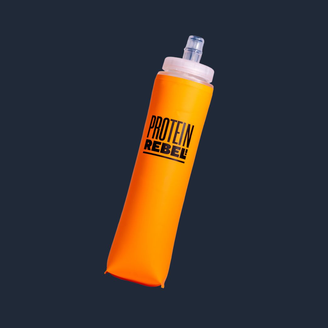 An orange collapsible water bottle sleeve with a clear cap and straw, featuring the black text 'PROTEIN REBEL' on the front, shown against a dark navy background.