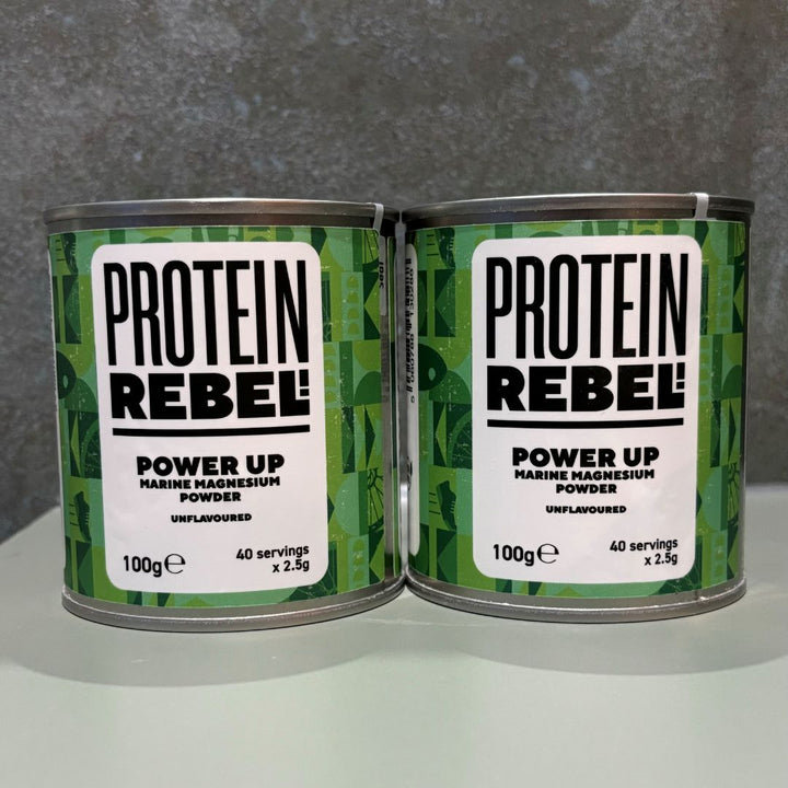 Two tins of Power Up magnesium citrate powder on a work surface